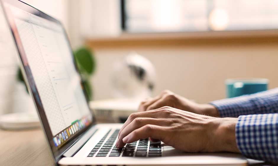 man-checkered-shirt-typing-computer