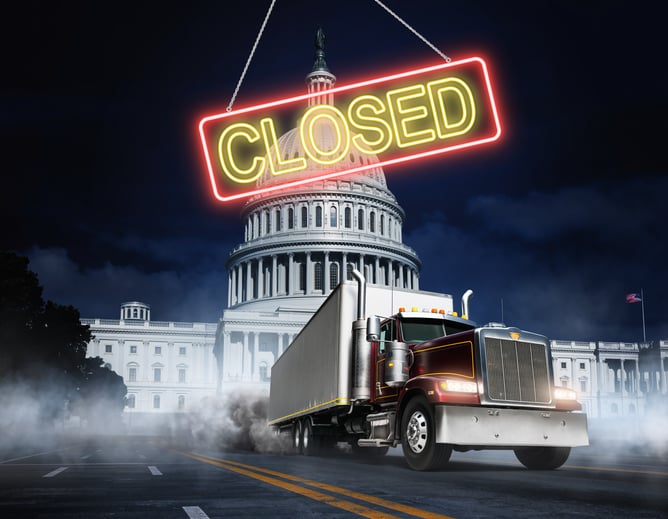 A neon "CLOSED" business sign hangs over the U.S. capitol. In the foreground, a semi truck with a dry van trailer screeches to a halt.