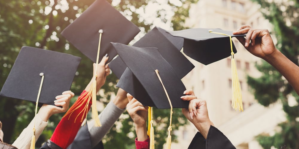 Group holding graduation caps in the air