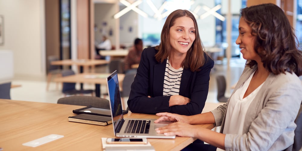 Two women talking in open office
