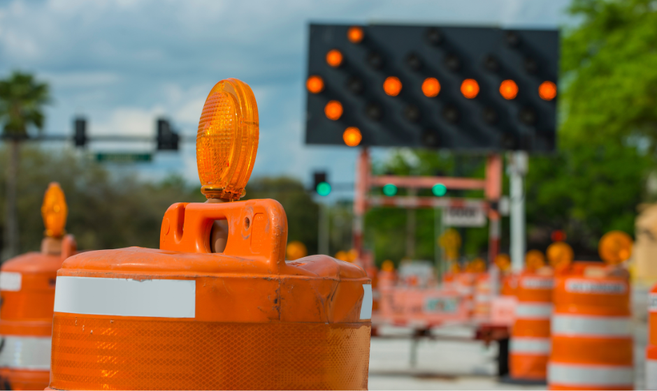 Traffic cones and a lighted detour sign with an arrow facing left