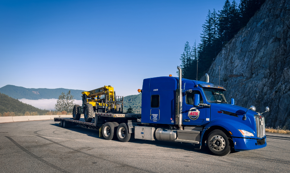 A flatbed truck carrying heavy haul equipment