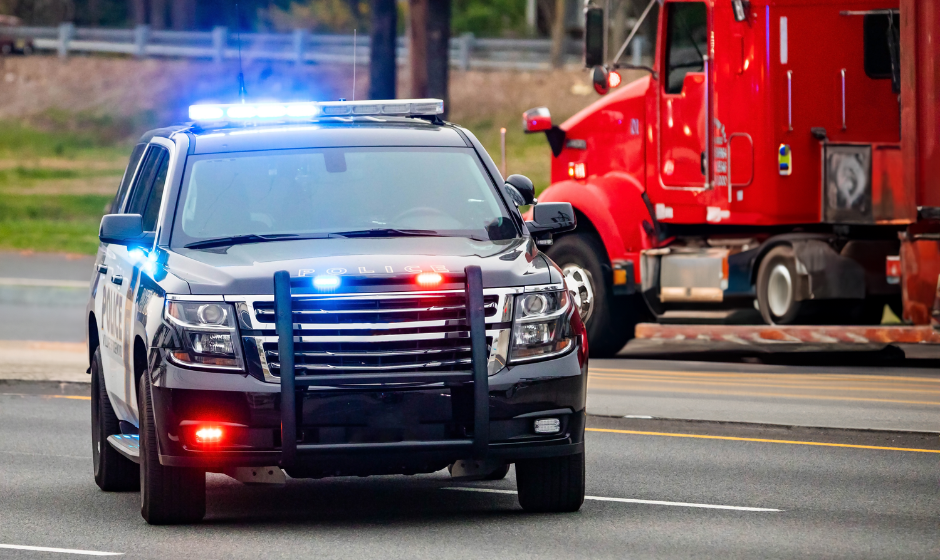 A patrol car blocks traffic for a semi truck