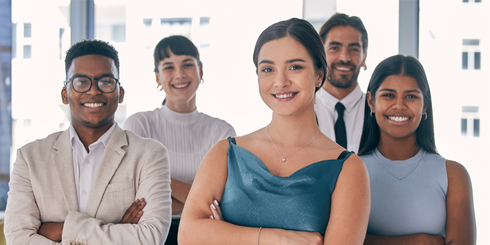 Young business professionals smiling at the camera with their arms crossed.