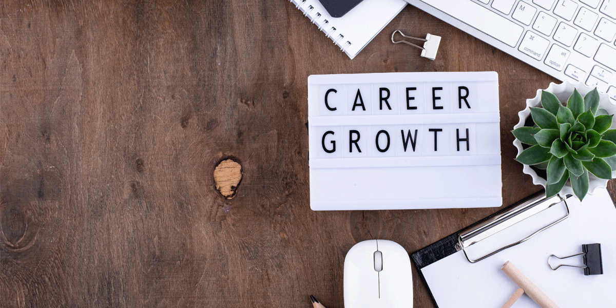 Flat lay with career growth sign, plant, keyboard, mouse, pencil, and other work tools.