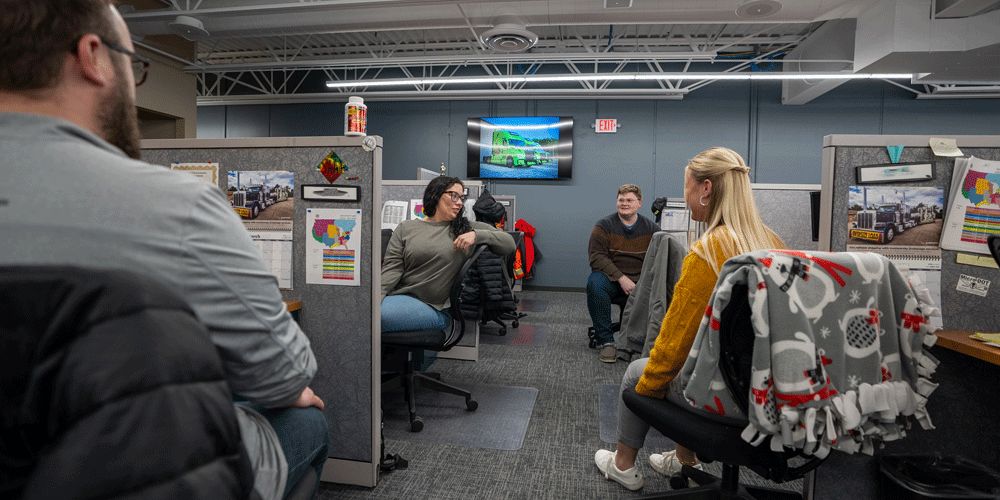 Coworkers at their desks chatting.