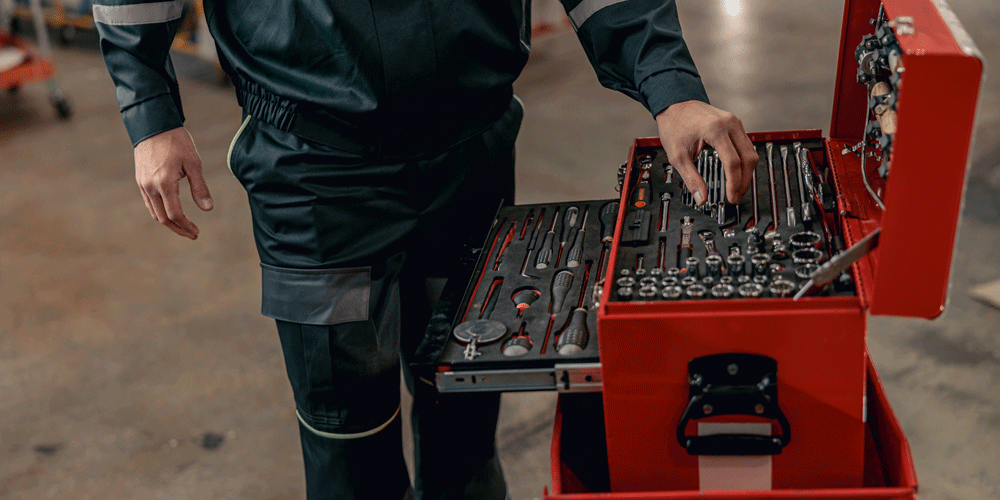 Man reaching for tools in mechanic toolbox.