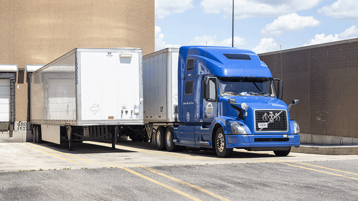 An ATS truck hauling a dry van trailer is loaded at a loading dock.