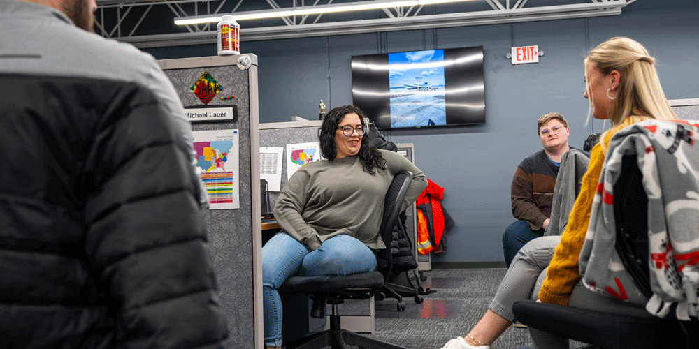Smiling employees in cubicles.