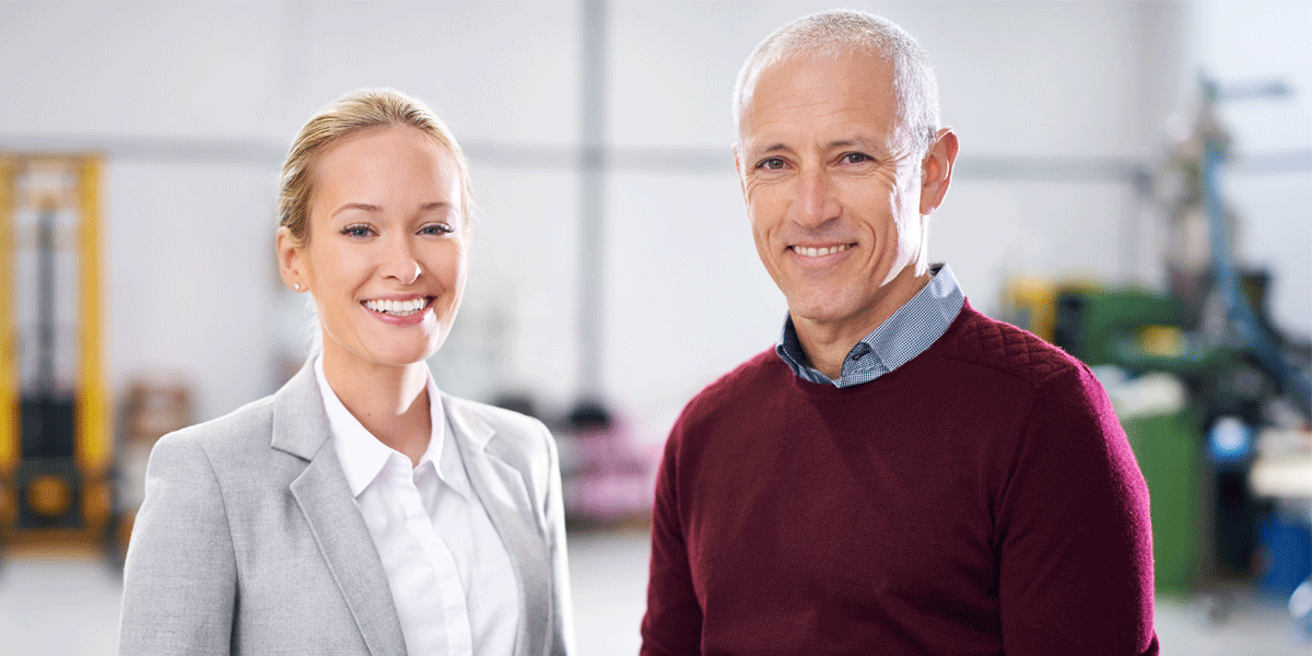 Two older salespeople smile. 