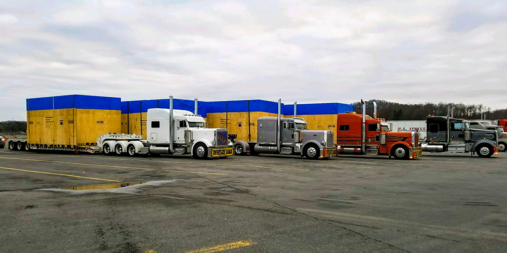 Several trucks carrying oversized cargo in a parking lot.