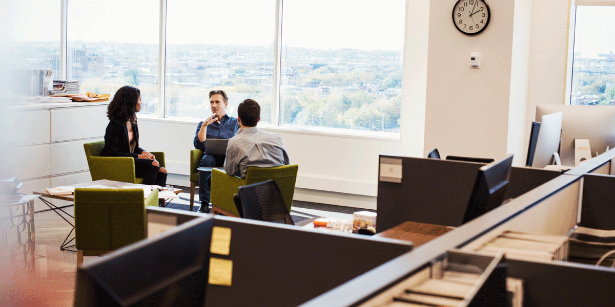 Woman and two men meeting in an empty office space.